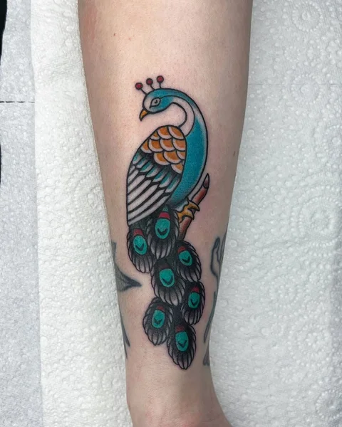 Colourful peacock tattoo with blue, gold and green feathers, by Brodie Bailey
